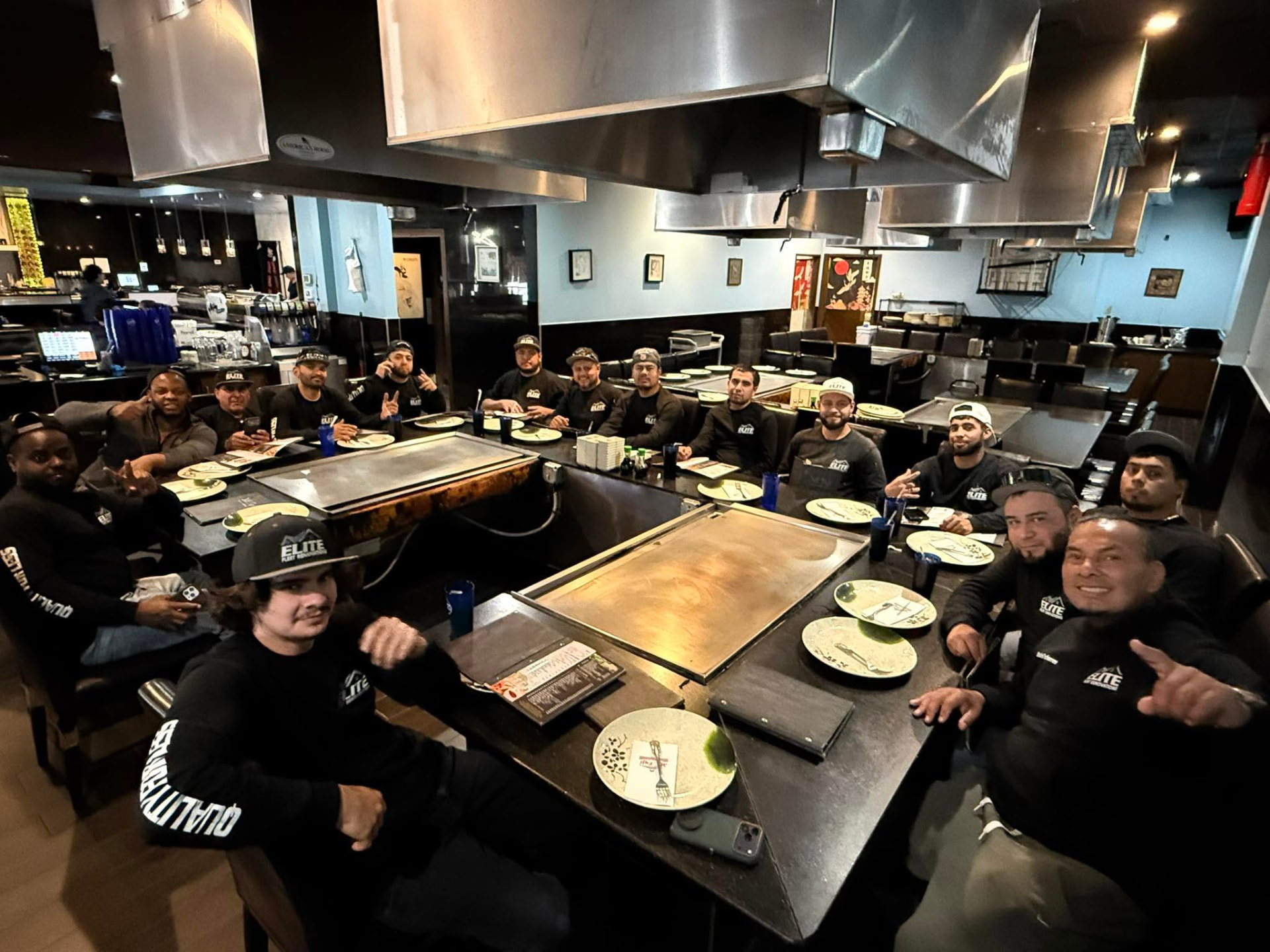 The Elite Fleet Renovations crew together at a team dinner wearing company shirts and hats